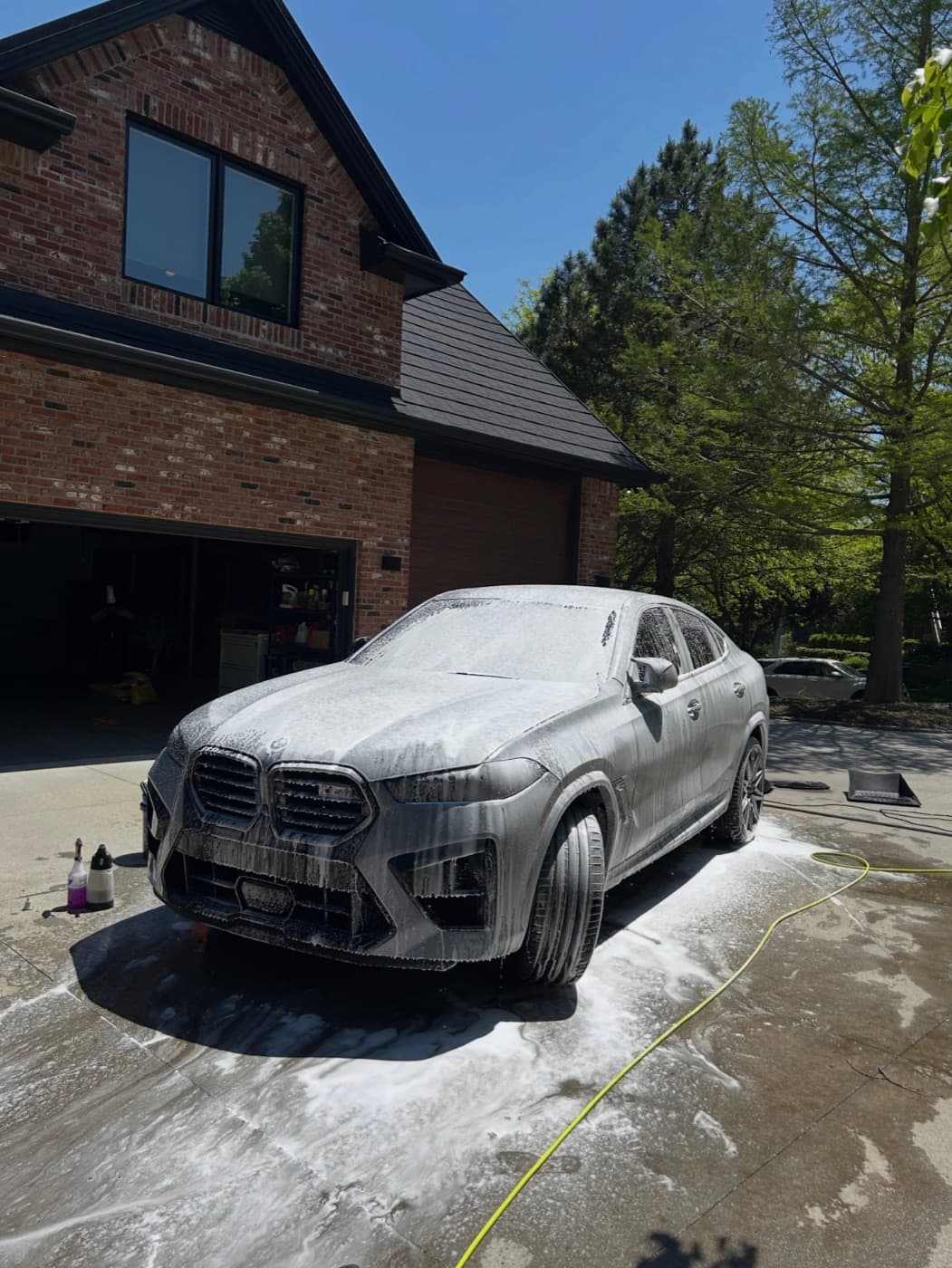 Foam-soaked SUV on a driveway during a hand wash